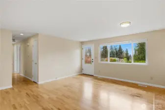 Light filled living space with gleaming hardwood floors.