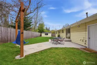 Fully fenced backyard with patio, level lawn, storage shed, and outdoor space.