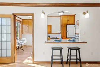 The sun-drenched eat-in kitchen seamlessly connects to the living room’s eating bar, creating a bright and inviting space for cooking, dining, and gathering.