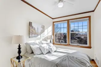 The cozy bedroom is bathed in natural light throughout the day, thanks to its wall-to-wall, south-facing window, offering serene city views and breathtaking sunsets to unwind by.