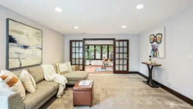 Expansive lower-level living space highlighted by elegant French doors, offering seamless flow into the bright sunroom.