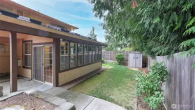 Step out from the sunroom into this charming side yard, perfect for gardening or creating a quiet retreat beneath the trees.
