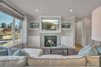 Living room features a gas fireplace with custom built-ins and large picture window bringing in natural light.