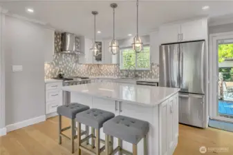 Stylish kitchen with quartz island, custom tile backsplash, and modern pendant lighting.