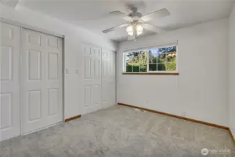 Spacious bedroom with new carpet, dual closets, and views of the backyard.