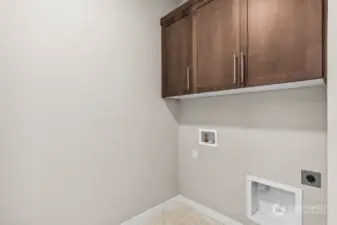 Convenient upstairs laundry room with storage cabinets.