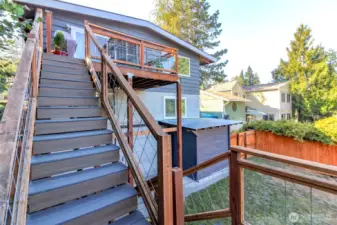 Stairs leading from the deck to the fully-fenced backyard with a storage shed.
