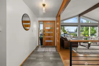 A look back toward the entry shows a perfect example of the balance of modern upscale finishes & convenience (new stair rail, durable lux vinyl plank floor in entry, and stylish new door & lighting) against the backdrop of original character.