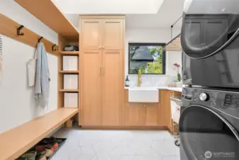 Convenience meets thoughtful design in the main floor laundry room, a true multitasking marvel. This space isn’t just functional—it’s elevated, featuring built-ins that provide a seamless flow and drop zone for life’s everyday necessities. Countertops offer plenty of room for folding and organizing, while heated tile floors add a touch of indulgent warmth to your daily routine. It’s a detail that ensures even household chores feel like a luxury.