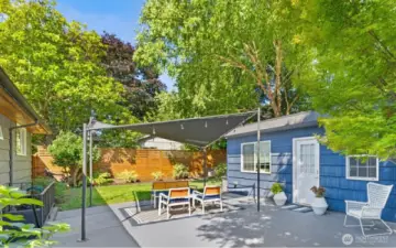 The main house is to the left and the studio apartment is to the right. The lush yard is shaded by lovely trees.