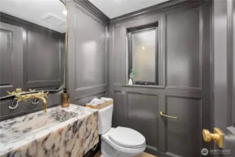 Main level powder room with panache! Complete with a custom stone sink, gold fixtures and custom millwork.