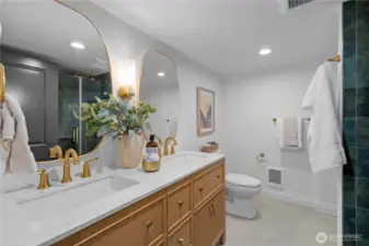 lower level 3/4 hall bath featuring a double-sink vanity with quartz counters, custom tile and a glass shower enclosure...
