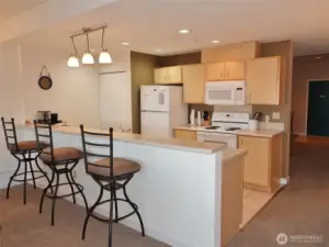 Kitchen has a full-length Eating Bar; tile floors; laminate counters; lots of counter and cabinet space; D/W, Range, Microwave, Refrigerator; and a stackable washer/dryer in the closet.
