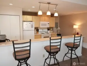 Kitchen has a full-length Eating Bar; tile floors; laminate counters; lots of counter & cabinet space; D/W, Range, Microwave, Refrigerator; and a stackable washer/dryer in the closet.