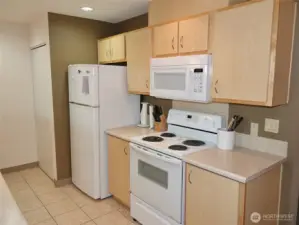 Kitchen w/ tile floors and plenty of cabinets and counter space.