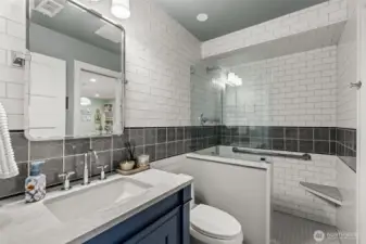 The downstairs bath has quartz countertops and custom tile work.