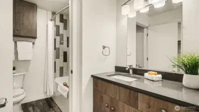 Bathroom from primary bedroom. Upgraded lighting and quartz counter. additional cabinets and big soaking tub!