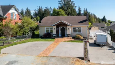 Paved parking in both the driveway and in front of the house with stamped concrete pathway.