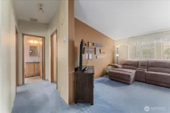 View from the living room down the hallway toward the entrances to the second and third bedrooms and shared bathroom