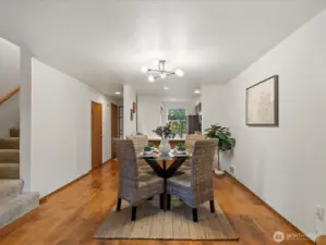 Dining space has updated lighting, with stairs leading to the second floor and utility/storage closet to the left
