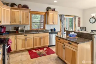 The kitchen combines hickory cabinets, elegant granite counters, and classic ceramic tile flooring.