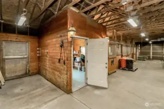 Wash station to the left with hot and cold water and floor drain. The open door is to the tack room and has a deep utility sink in it as well. Concrete center aisle and in the tack room and wash station area.