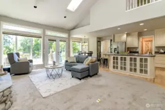 This view of the great room show the kitchen and informal dining room off of the kitchen. French doors lead to the composite deck and second set of French doors lead to the office.  Built in china cabinets face the great room. This room has tall vaulted ceilings and a celing fan with canned lighting.