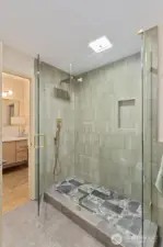 Luxurious walk-in shower with art deco floor design, brushed gold fixtures & custom tile surround.