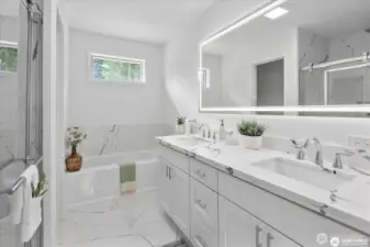 Spa like bathroom in the primary bedroom, with custom tile, quartz counters and LED mirror.