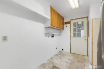 Laundry room with upper storage cabinets and convenient exterior access.