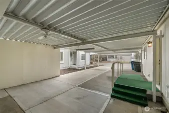 Large covered carport with protected parking and attached shop/storage area.