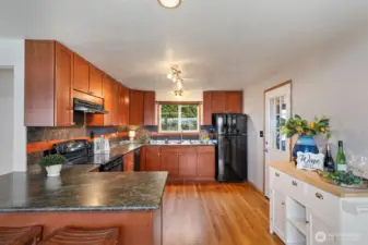 Updated kitchen with oak floors and leathered granite slab counter tops. Utility room/laundry room to the right.