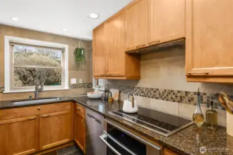 The kitchen features updated stainless steel appliances, a new kitchen hood vent, wood cabinetry and slate flooring.