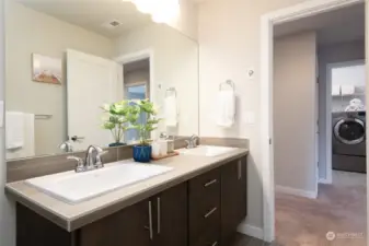 Upstairs guest bathroom with dual sinks and easy access to the laundry room.