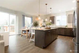 The large kitchen is sure to please with multiple work spaces and entertainment sized island with pendant lighting. It enjoys an  abundance of storage and counter space. Warm wood tones and custom granite counters create an elegant and inviting room.