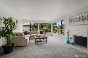 A spacious and inviting living room, complete with a fireplace for cozy evenings and expansive corner windows that fill the home with natural light.