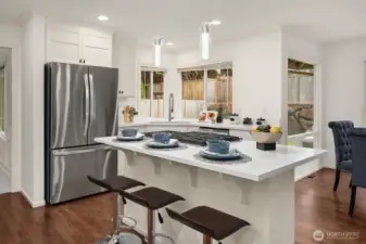 A sleek, well-designed kitchen offers abundant storage, premium stainless steel appliances, and a large island with bar seating, all bathed in natural light from the surrounding windows.