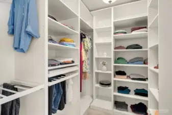 The expansive walk-in closet features custom built-ins with dedicated hanging, shelving, and storage sections, offering exceptional organization and a boutique-like experience every day.