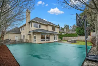 The expansive backyard features a full sports court and is framed by mature trees and privacy fencing, offering exceptional outdoor recreation space rarely found in this coveted Trossachs community.