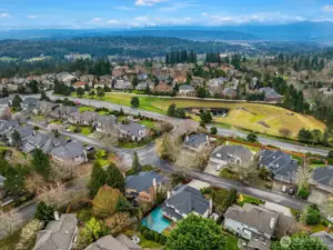 Situated in the highly desirable Trossachs community, this aerial view captures the beautifully maintained neighborhood surrounded by open fields, tree-lined streets, and stunning mountain views beyond.