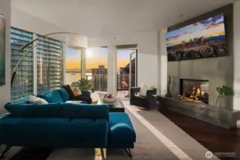 The open living space is filled with natural light and anchored by a dual-sided gas fireplace that seamlessly connects the living room and primary suite.