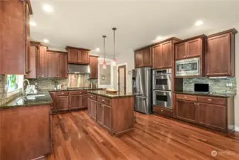 Spacious island kitchen clad with cherry cabinets, granite, tile accents and premium appliances.