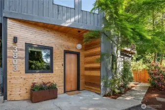 The lower entry offers convenient access to house through the rec room while the sidewalk to the right flows up to the main entrance off the deck.