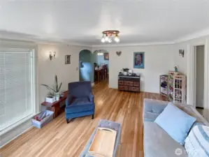 Original archways lead the way from the light-filled living room into the dining area, offering a layout that feels both classic and connected. Coved ceilings and original wall sconces nod to the home’s early 20th-century roots, while the warm hardwood floors add timeless appeal underfoot. This is a space where game nights, quiet mornings, and everything in between feel right at home.