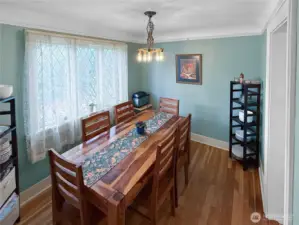 Gather in a dining room that radiates vintage charm, featuring original leaded glass windows that filter soft natural light through delicate lace curtains. The warm hardwood floors and classic chandelier create a perfect backdrop for holiday dinners or weeknight takeout alike. It’s a space that honors the home’s history while making everyday moments feel a little more special.