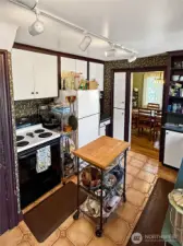 This cheerful galley kitchen offers plenty of storage, handy prep space, and a direct line of sight into the dining room — making mealtime a breeze. The movable island adds function, while the retro details give the space undeniable charm. Ready as-is or ripe for a stylish refresh, this kitchen has great bones and even better energy.