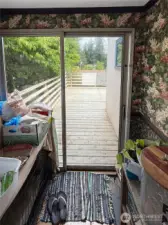 Step from your private office (or mudroom) out onto a generous back deck framed by mature trees—ideal for morning coffee, fresh-air brainstorming sessions, or al fresco evenings with friends. The vintage floral wallpaper inside nods to the home’s history, while the sliding glass door creates an effortless connection between cozy interiors and your own outdoor retreat.