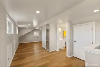 Vinyl planks cover extra insulated floors. Small doors along left wall give access to nicely finished storage space. On the right is a larger storage space/closet, a 1/2 bath, and a mirror front closet.