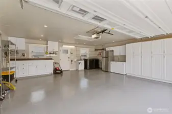 Additional cabinets and workbench area with door to backyard. 2nd laundry hook up in garage with utility sink and 2nd water heater (behind fridge). Washer/dryer and box freezer can stay. Refrigerator to go with sellers.