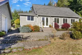 Garage to the left, pathway to patio and trex deck between house and garage, french doors entrance to kitchen/dining/living area